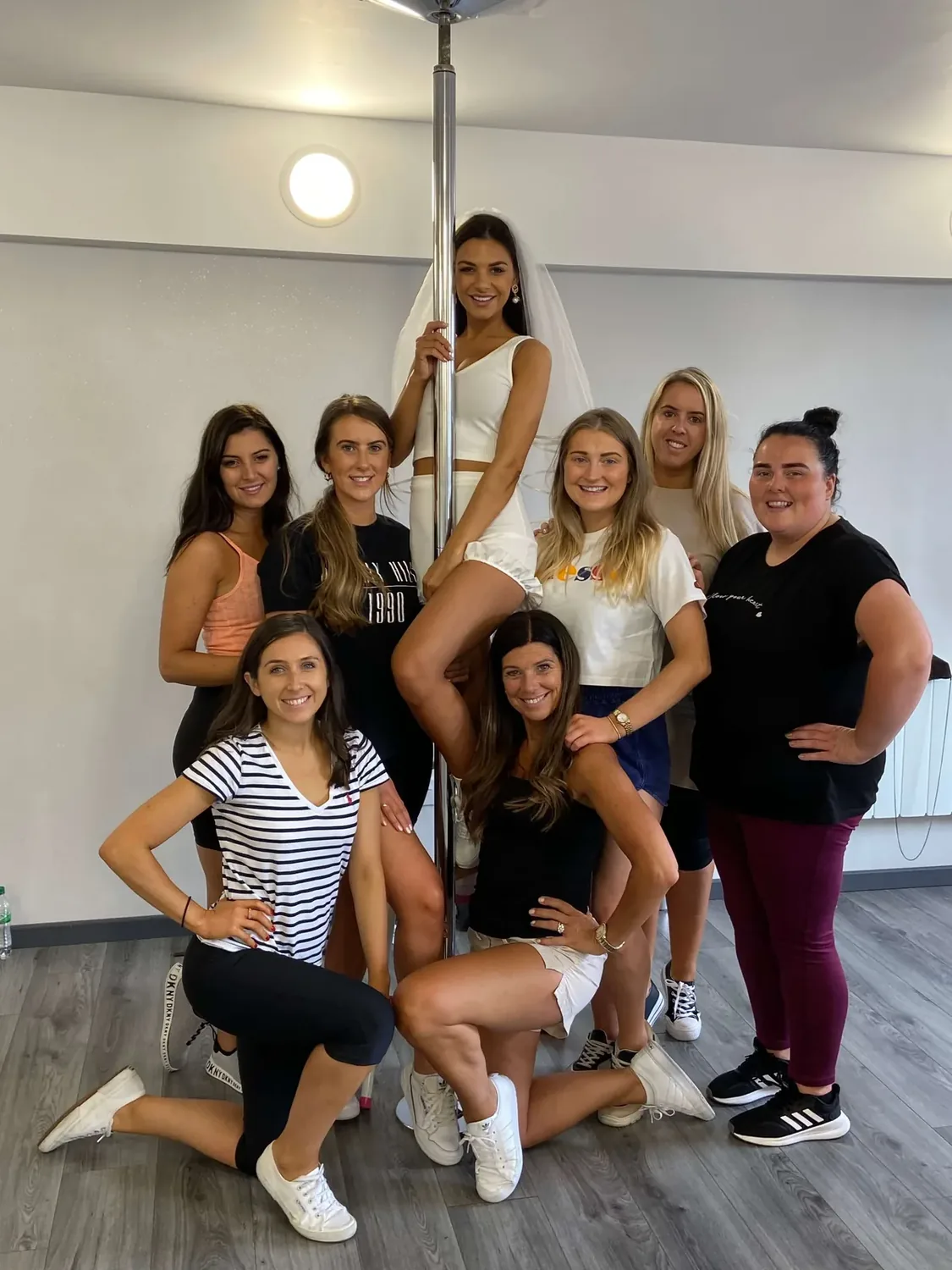 Pole dancing hen party dance class in Nottingham, group taking turns on the studio poles